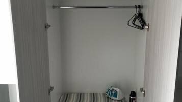 Un armario con varios estantes, una barra para colgar ropa y una toalla doblada.