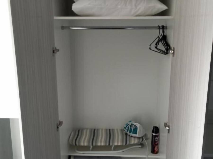 Un armario con varios estantes, una barra para colgar ropa y una toalla doblada.
