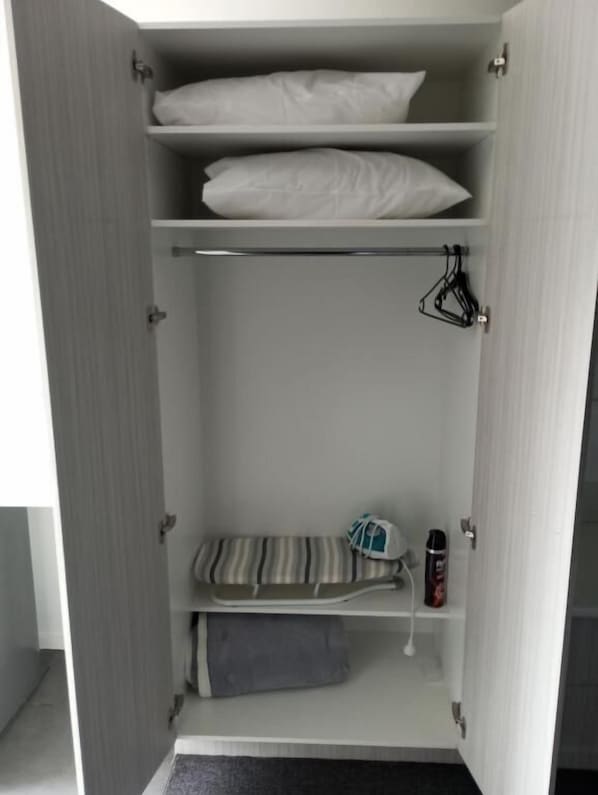 A wardrobe with multiple shelves, a hanging rod, and a folded towel. - Big Valley Lakeside Paradise Motor Inn (Shepparton)