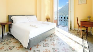 Ein Hotelzimmer mit Bett, einem kleinen Tisch, einem Sessel und einem Balkon mit Bergblick.