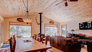 Amplia sala de estar con una mesa de comedor de madera, un sofá y una televisión.