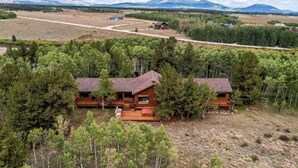 Una cabaña con terraza, rodeada de árboles y un paisaje montañoso.