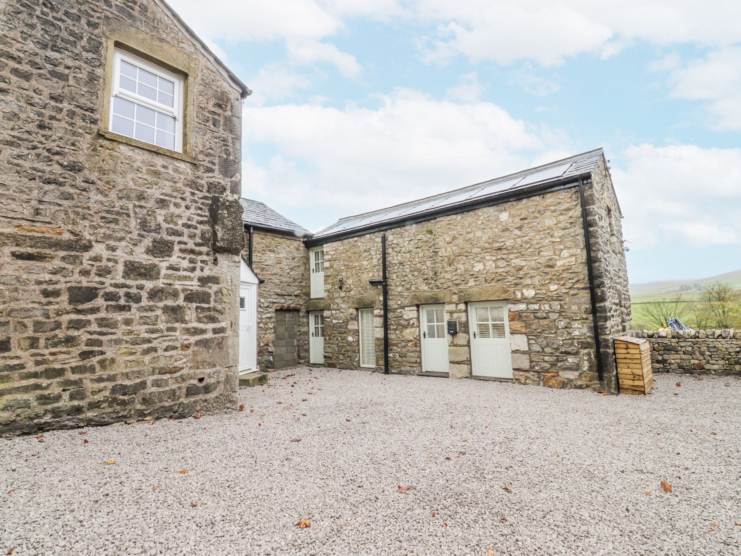 A stone building with a gravel courtyard, featuring multiple doors and windows.