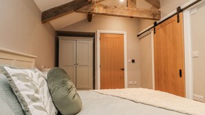 A bedroom with a bed, two doors, and a slanted ceiling. - Henside Cottage (Settle)