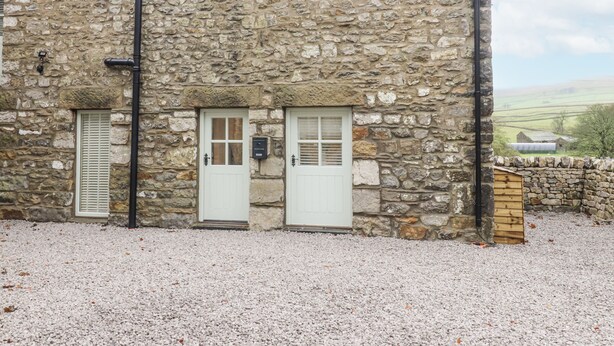 A stone building with two white doors and a small window. - Henside Cottage (Settle)