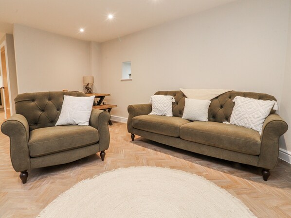 Sala de estar com dois sofás, uma mesinha e um tapete branco.