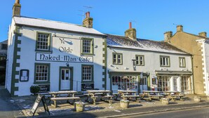 A traditional building with a sign reading "Olde Naked Man Cafe" and outdoor seating. - Henside Cottage (Settle)