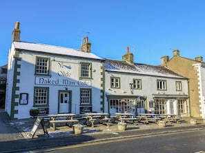 A traditional building with a sign reading 'Naked Man Cafe' and outdoor seating. - Henside Cottage (Settle)