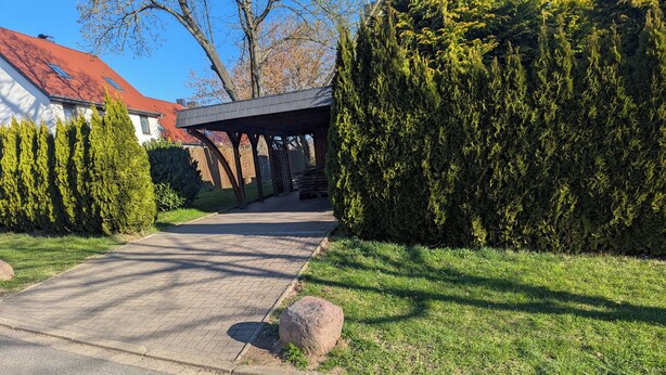Un camino de entrada residencial que lleva a una casa con porche cubierto.