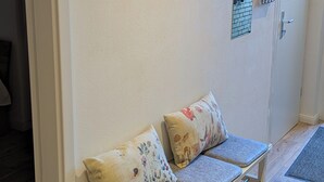 Un banco con cojines estampados en un pasillo con una puerta y un ventanal pequeño.