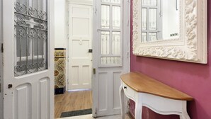 Un couloir avec une porte blanche, un miroir et un banc en bois.