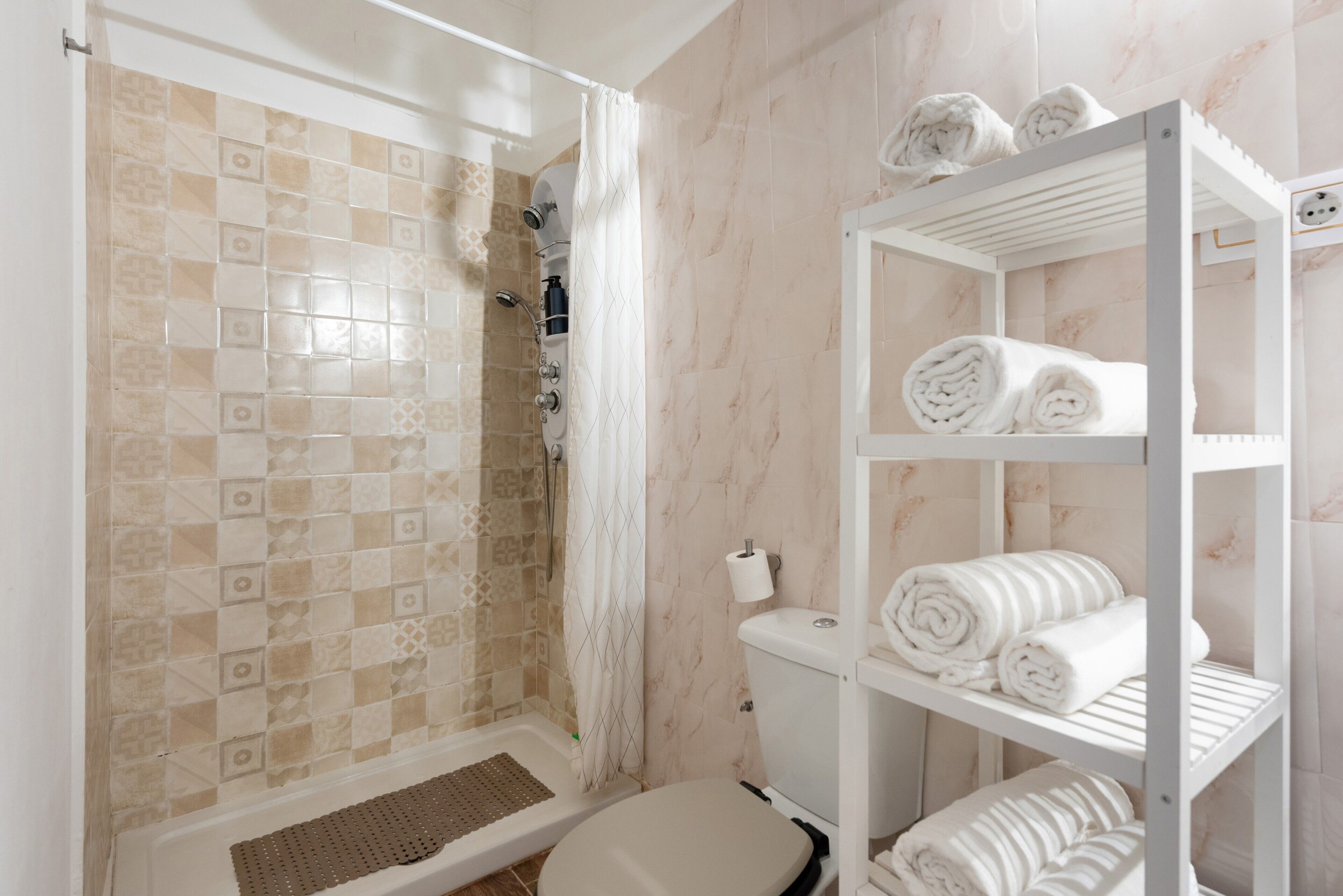 Un bagno con doccia, servizi igienici e mensole con asciugamani.