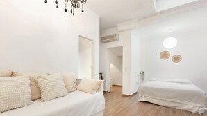 Une chambre à coucher comprenant un lit, un canapé, une table de chevet et un luminaire suspendu.