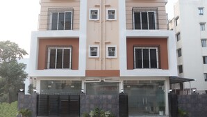 Un edificio de varios pisos con una fachada simétrica, que presenta una entrada central con puertas de vidrio y una verja de metal.
