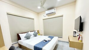 Una habitación de hotel con cama, escritorio, televisión y aire acondicionado.