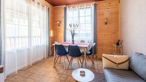 Una habitación con paneles de madera, una mesa de comedor, sillas, un sofá y una mesita con un tazón.