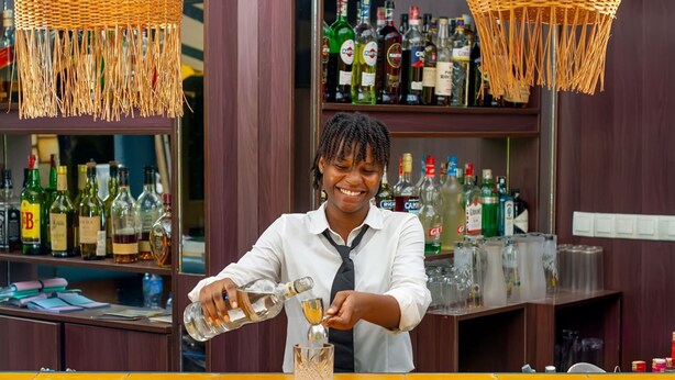 A bar setting with a bartender pouring a drink into a glass. - Hôtel Ô Balkan (Lomé)
