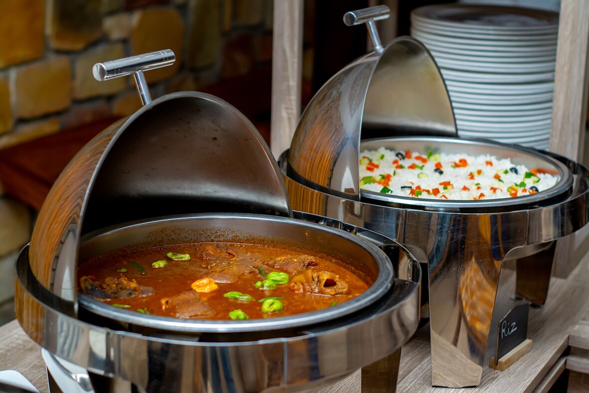 Two large metal chafing dishes, one containing a stew and the other rice with vegetables.