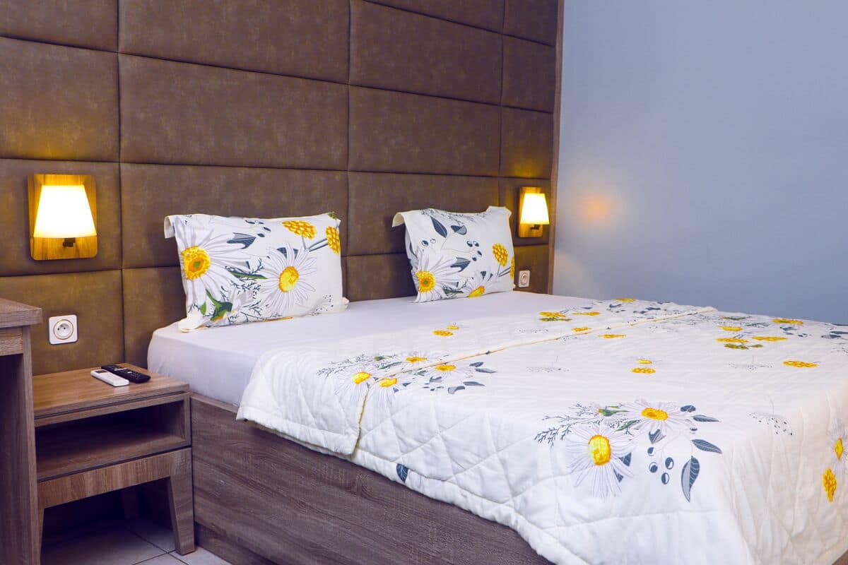 A bedroom with a bed, nightstands, and wall-mounted lamps.