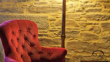 A red upholstered armchair next to a wooden table with a lamp and a book.