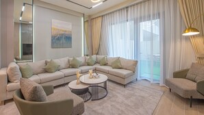 Una sala moderna con un sofá modular, una mesa de centro redonda y vistas al exterior a través de amplios ventanales.