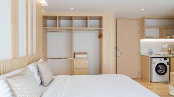 A bedroom with a bed, a wardrobe, and a washing machine.