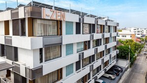 A multi-story residential building with a modern design, featuring balconies, large windows, and a parking area with several cars. - I-Zen Residence Central Eastville (Bangkok)