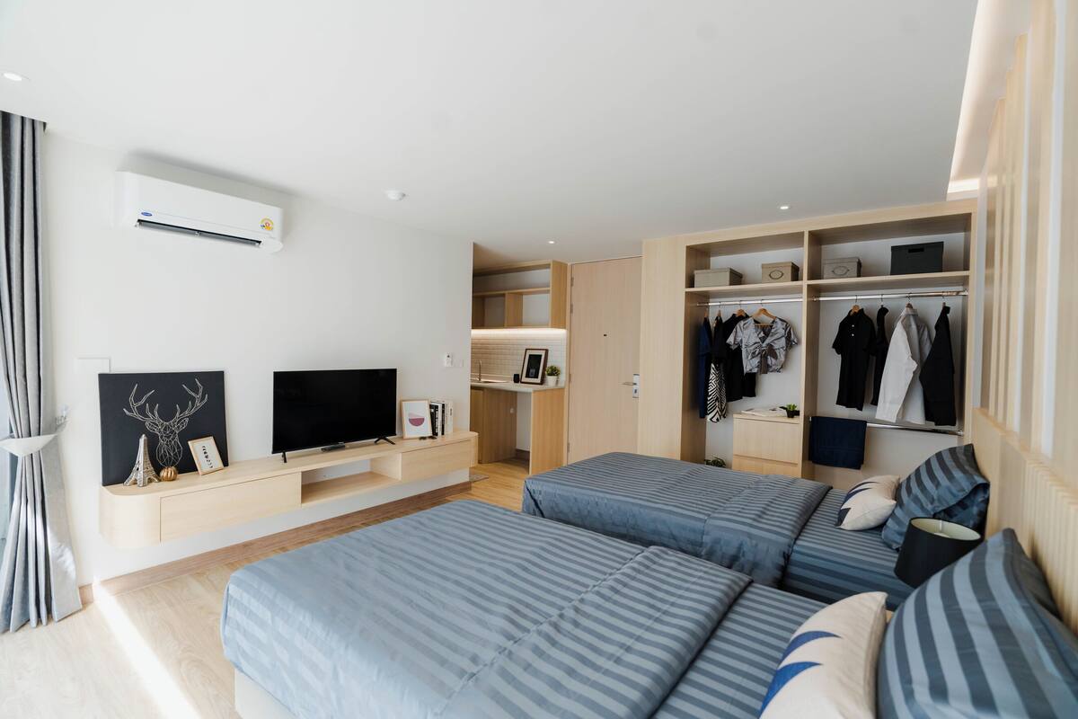 A modern bedroom with two beds, a TV, and a walk-in closet.