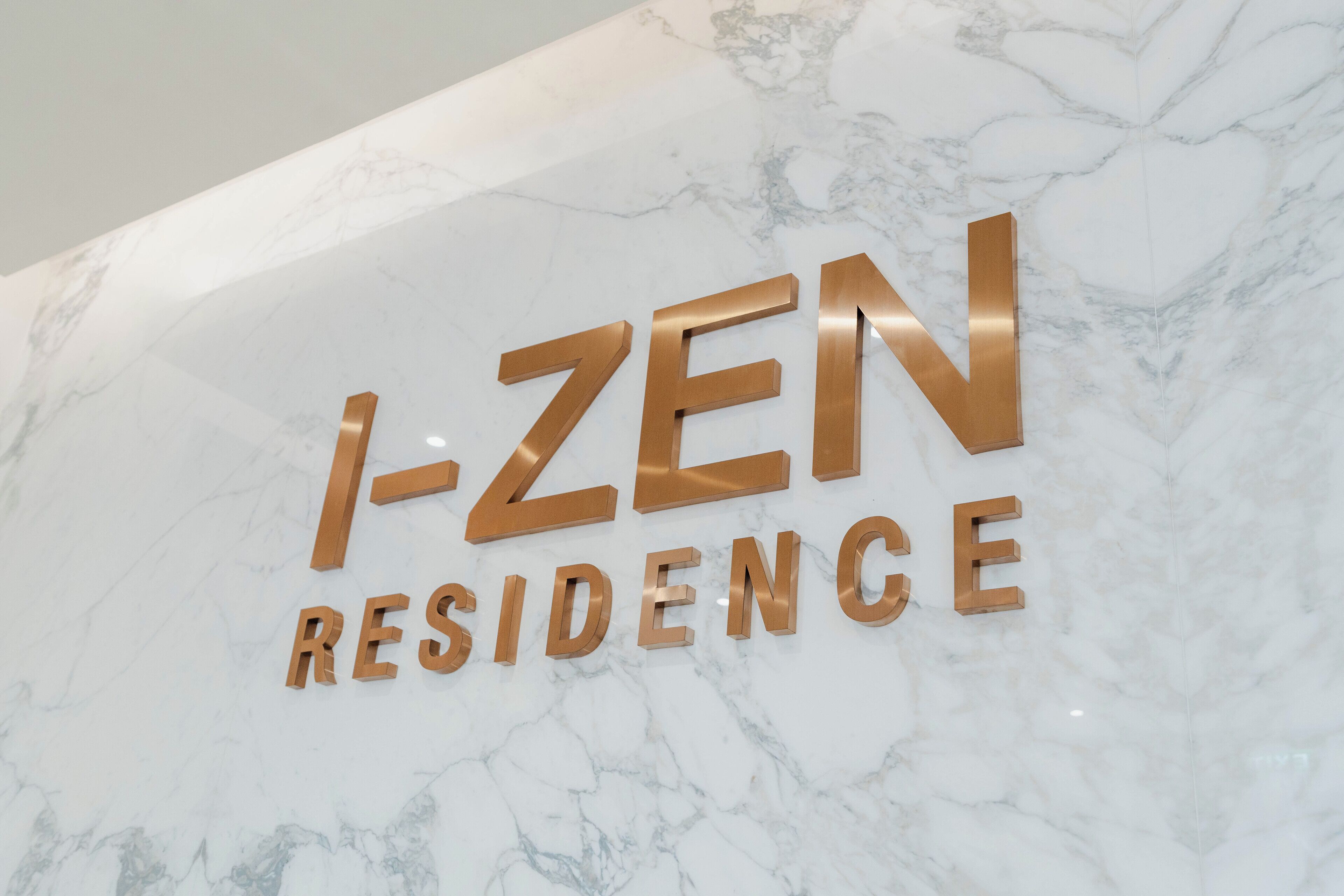 A marble wall with the text "I-ZEN RESIDENCE" in gold letters.