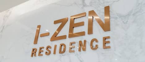 A marble wall with the text "I-ZEN RESIDENCE" in gold letters.