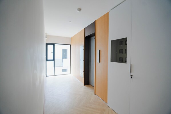 Un pasillo moderno con un panel de madera en la pared, una puerta con picaporte y un interruptor de luz.
