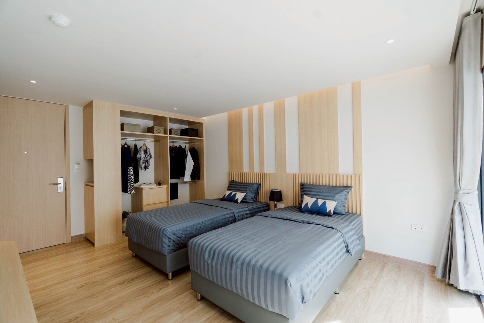 A bedroom with two beds, a wardrobe, and a mirror.
