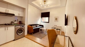 Un espacio habitable compacto con cocina, sofá, mesa de comedor y lavadora.