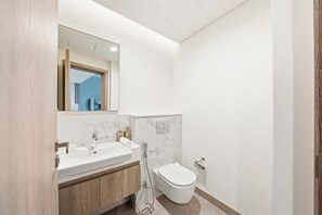 Ein modernes Badezimmer mit Waschbecken, Spiegel und Toilette in Weiß.