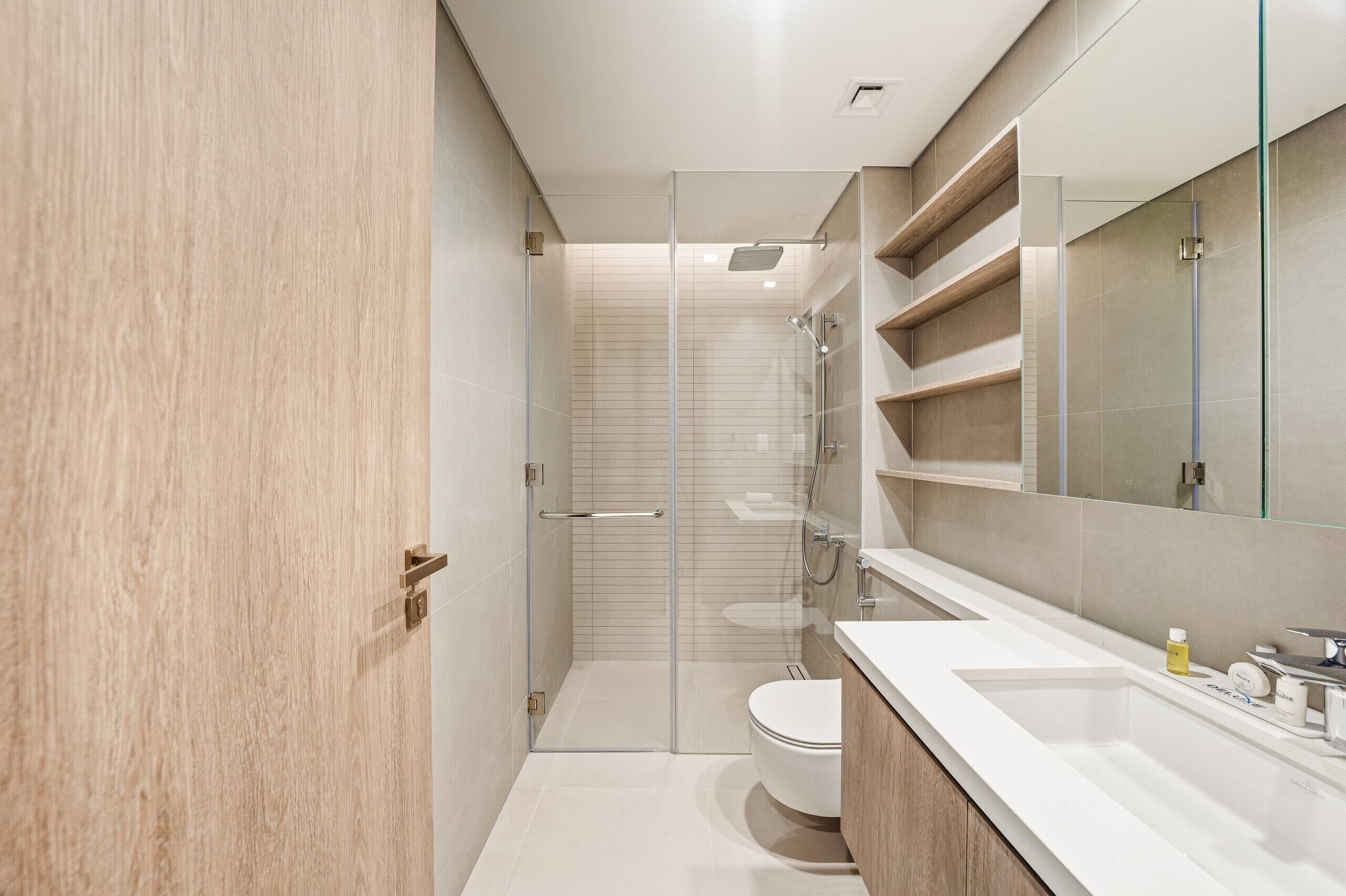 A modern bathroom with a glass shower enclosure, a white toilet, and a vanity with a mirror.