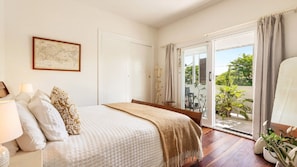 Ein Schlafzimmer mit einem Bett, einer Karte an der Wand und Blick ins Freie durch eine Schiebetür.