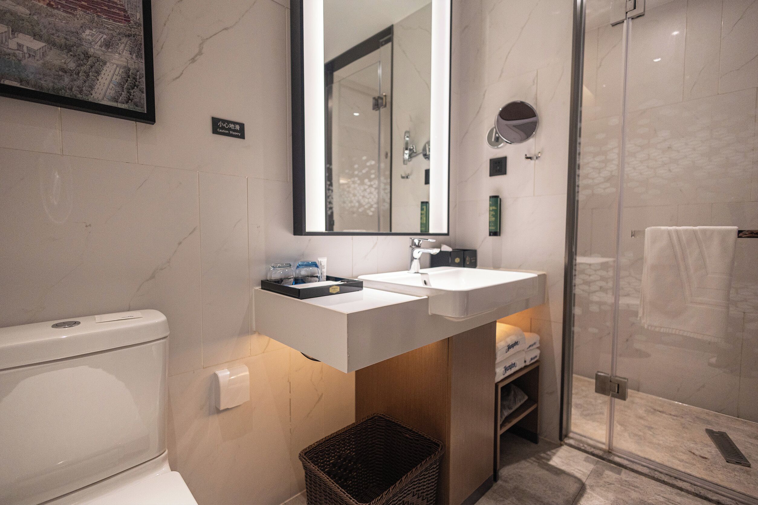 A modern bathroom with a toilet, sink, mirror, and shower.