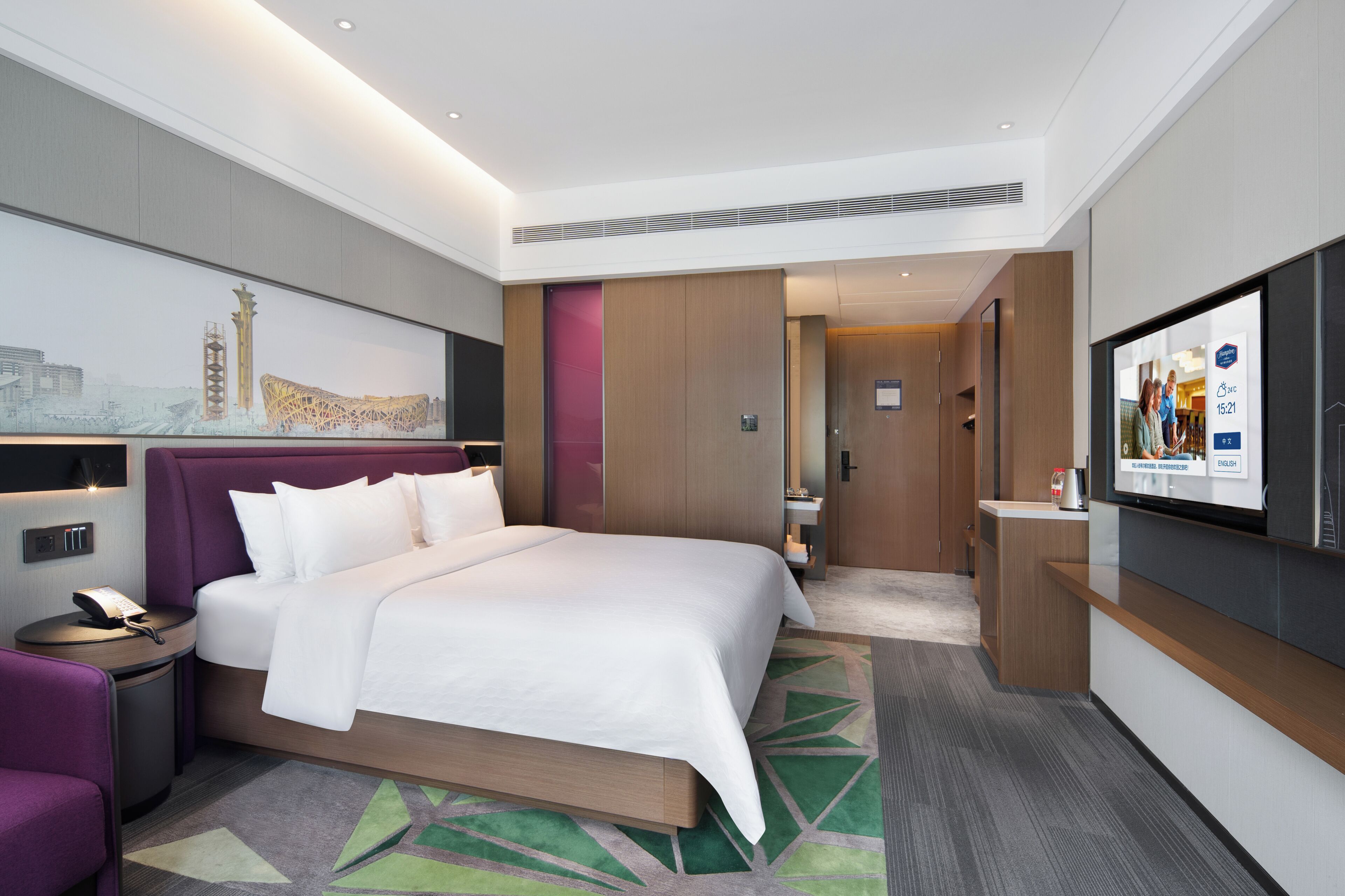 Une chambre d’hôtel moderne dotée d’un grand lit, d’une télévision à écran plat, d’un bureau et d’un coin salon.