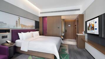 Une chambre d’hôtel moderne dotée d’un grand lit, d’une télévision à écran plat, d’un bureau et d’un coin salon.