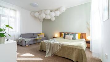 A bedroom with a bed, a sofa, a bedside table, a lamp, and a wall decoration.
