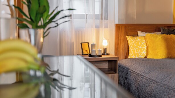 Ein Hotelzimmer mit Bett, Nachttisch und einer Topfpflanze.