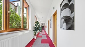 Ein Korridor mit rotem und grauem Teppich, Topfpflanzen und einer Treppe am Ende.