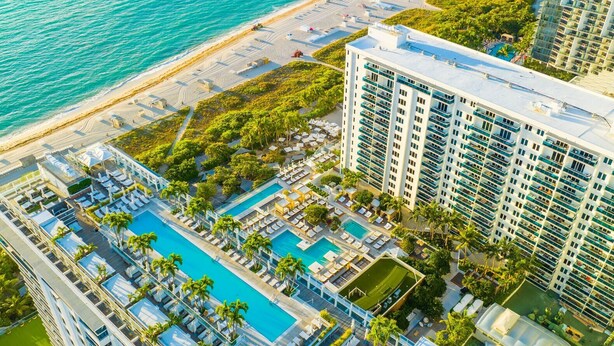 Un hôtel de grande hauteur doté de plusieurs piscines, d’une plage et d’une végétation luxuriante.