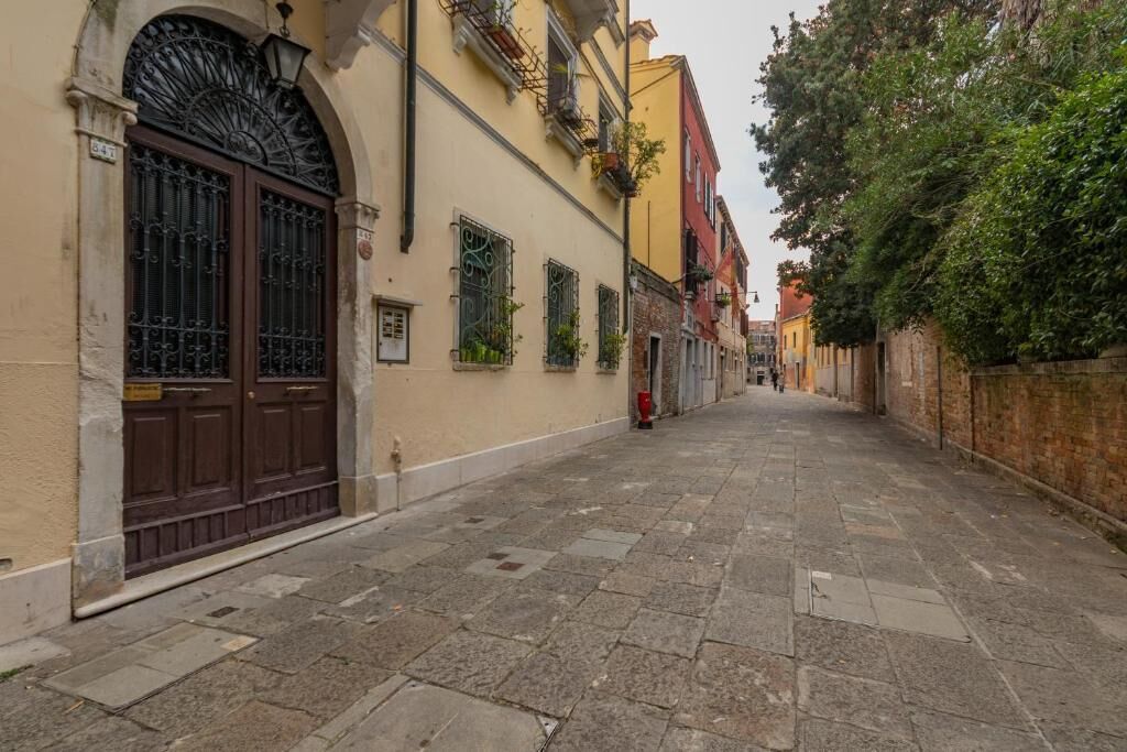 A narrow street with historic buildings, a large wooden door, and a red fire hydrant.