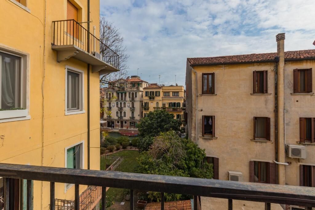 A yellow building with a balcony and a view of other buildings in the background.