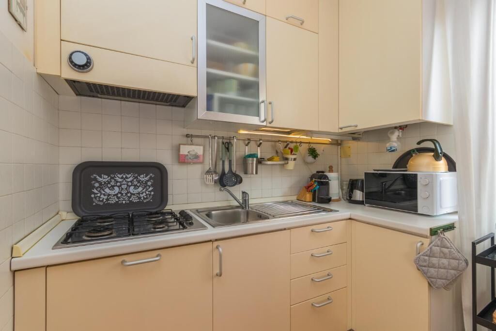 Una cocina con estufa, microondas y alacenas.