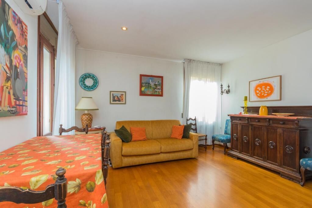 A room with a bed, a sofa, a wooden cabinet, and a dining table.