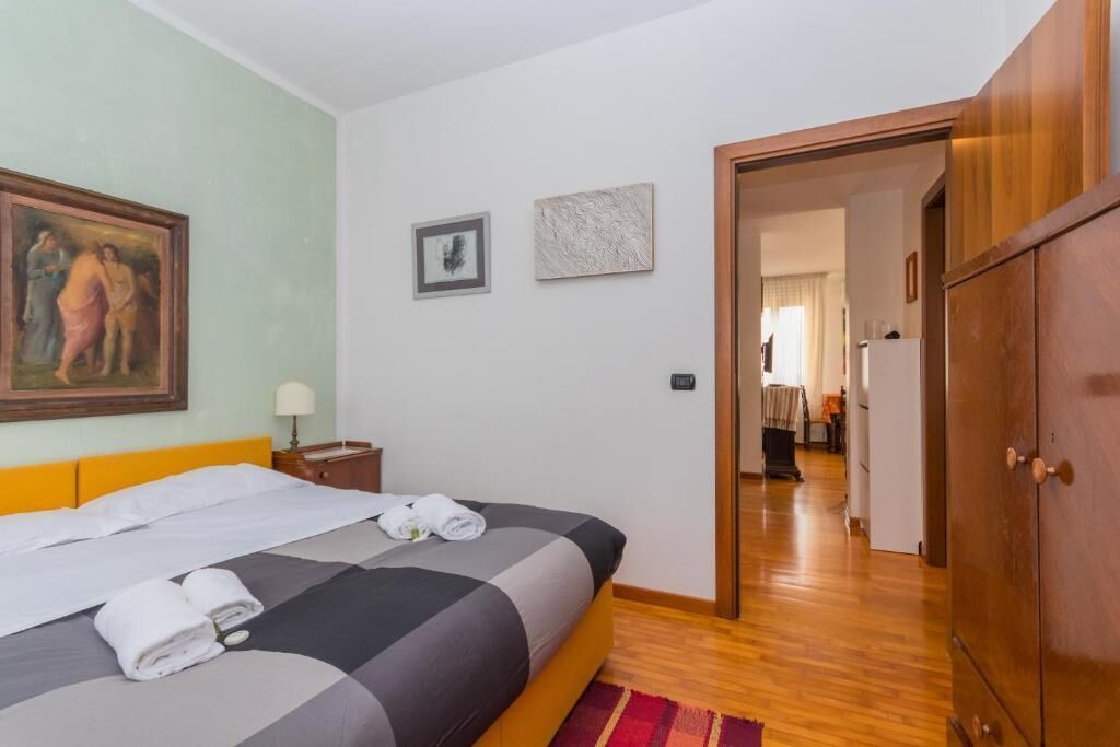 Habitación de hotel con cama, un cuadro y una puerta que da a otra habitación.
