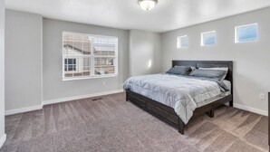 A bedroom with a bed, a window, and a ceiling light. - Comfort Stay w/ Studio • Thanksgiving Point (Lehi)