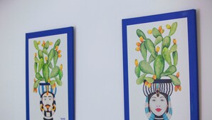 Dos obras de arte enmarcadas que muestran plantas con rostros humanos, una con un borde azul y la otra con un borde blanco.